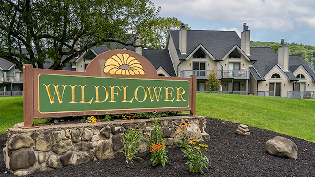 The entry sign to the Wildflower condos with units in the background on a sunny summer day.